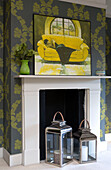 Hurricane lanterns in fireplace of Berkshire bedroom with patterned wallpaper, England, UK