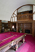 Pink pool table in panelled games room of London home with balcony, UK