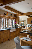 Butler sink and at brick windows in wood fitted kitchen of London home, UK