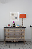 Orange lamp on vintage chest of drawers in London townhouse England UK