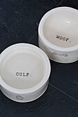 Two white dog bowls with single words 'GULP' and 'WOOF' in London townhouse England UK