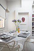 Modern artwork with dining table and chairs at window in London townhouse England UK