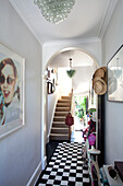 Framed artwork and sunhats with checked rug in hallway of London townhouse, England, UK