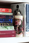 variety of books with skull on spray can in London townhouse, England, UK