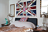 Union Jack flag above double bed with matching chrome lamps in London home, England, UK