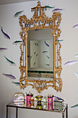 Fish swim on wall behind gilt-framed mirror in bathroom detail of London home, England, UK