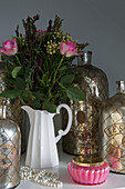 Pink roses with vintage silver bottles in Sussex home  UK