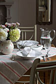 Striped tablecloth on dining table with napkins on bowls in UK home