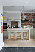 Three wooden barstools at breakfast bar in Shoreham by Sea kitchen   West Susses   England   UK