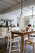 Glass pendant lights above wooden table with benches in flagstone kitchen of London home,  England,  UK