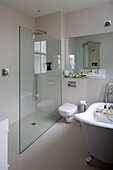 Glass shower screen in cream bathroom with freestanding bath,  Hertfordshire home,  England,  UK
