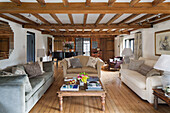 Wooden coffee table and sofas with grand piano in beamed living room of Sussex cottage   England   UK