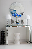 Pair of matching lamps with circular mirror and wine rack on mirrored console in contemporary London home   UK