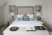 Framed artwork and lamps with books on at foot of double bed in contemporary London home   UK