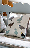 Duck pattern on cushion of bench seat in UK farmhouse