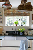 Double sink with mixer tap at window in UK farmhouse kitchen