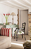Gepolsterter Sessel am bemalten Schreibtisch mit Calla-Lilien und Sichtmauerwerk in einem Londoner Haus, England, UK