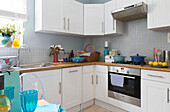 Weiße Einbauküche mit grauen Kacheln in einer modernen Wohnung in London, England, UK