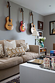 Wall-mounted guitars above sofa in London living room,  England,  UK