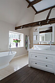 Freistehende Badewanne und Waschbecken in einem zweistöckigen Haus mit Balken in Surrey, England, UK