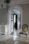 Dining chair on marble flagstones with arched entrance hallway in Surrey home,  England,  UK