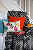 Gift wrapped presents on sofa with baubles on cushion in Dronfield home  Derbyshire  England  UK