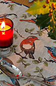 Lit candle on table runner with robin in Dronfield home  Derbyshire  England  UK