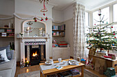 Christmas presents below tree with lit fire in living room of Dronfield home  Derbyshire  England  UK