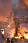 Cotton buds and soaps in storage jars with lit candles in Laughton bathroom  Sheffield  UK