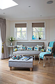 Floral cushions on sofa below windows in living room of London home   England   UK