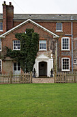 Fenced lawn and porch entrance to brick Georgian farmhouse in King's Lynn  Norfolk  England  UK