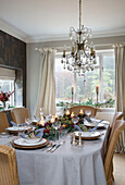 Glass chandelier above dining table set for six at Christmas in Chobham home   Surrey   England   UK