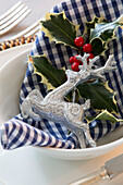 Silver reindeer ornament with holly and gingham checked napkin in place setting on Chobham dining table   Surrey   England   UK