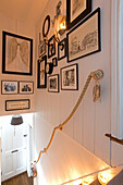Framed artwork displayed above rope handrail in staircase of Surrey home   England   UK