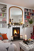 Large mirror above lit fire with bookshelves in Surrey living room   England   UK