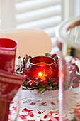 Lit tealight with berries on dining room table in Surrey home   England   UK