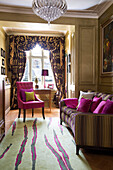Rosa Sessel und Kissen mit üppigem Vorhang im Wohnzimmer eines Londoner Stadthauses England UK