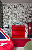 Bright red chest of drawers with postbox and patterned wallpaper in child's room of London townhouse   England   UK