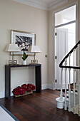 Pair of lamps on wooden console in staircase hallway in London townhouse   England   UK