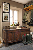 Sunhat on wooden chest with boots and jackets in Warminster country house  Wiltshire  England  UK
