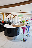 Curved breakfast bar with stools in modern kitchen of Sandhurst country home  Kent  England  UK