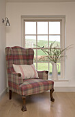 Tartan armchair at window of East Dean farmhouse  West Sussex  UK
