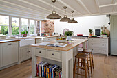 Brass pendant lights hang above kitchen island in East Dean farmhouse  West Sussex  UK