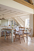 Wooden dining chairs at table in open plan East Dean farmhouse  West Sussex  UK