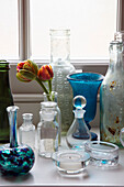 Vintage-Flaschen und Vasen mit Tulpen auf der Fensterbank in einem Haus in Surrey, England, UK