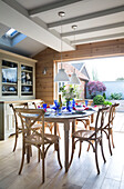 Blue glassware on dining table with open access to garden terrace in Surrey home,  England,  UK