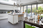 Pendant lights above breakfast bar in open plan kitchen extension of contemporary London home, England, UK