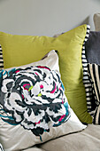 Floral patterned and yellow cushions on sofa in contemporary London home, England, UK