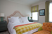 Karierte gelbe Decke auf einem Doppelbett mit Chaiselongue in einer Wohnung in London, England, UK