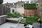 Raised beds and flowering plants in urban courtyard garden of London home, England, UK